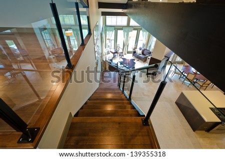 Entrance to the luxury upper home level  with the spacious living room downstairs. View from atop.  Interior design.
