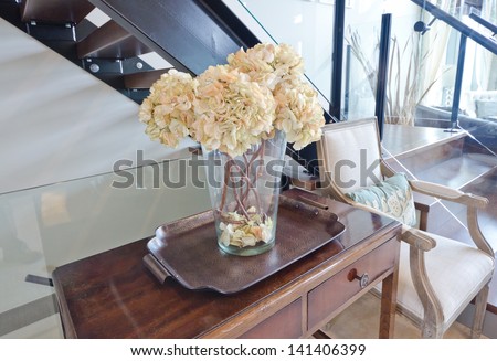 Vase with some flowers on the tray and on the table. Interior design. Fragment.