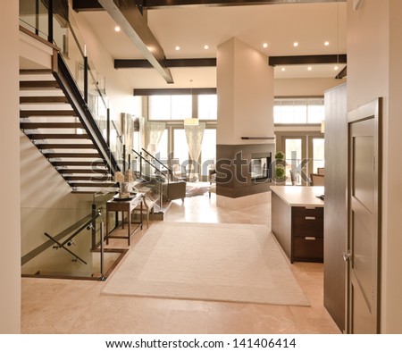 Outlook at the luxury spacious modern living room with the fireplace and stairs to the upper level. Interior design.