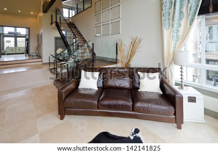 Outlook at the luxury spacious modern living room with the leather sofa, coach at the front and stairs to the upper level. Interior design.