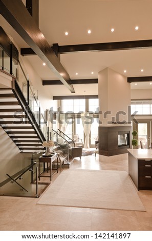 Outlook at the luxury spacious modern living room with the fireplace and stairs to the upper level. Interior design. Vertical.