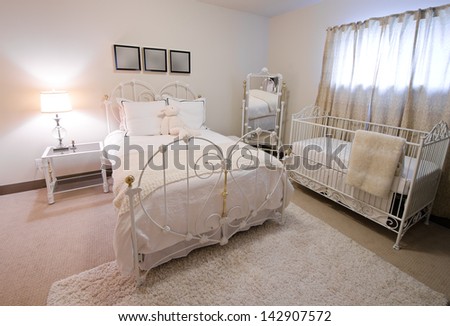Interior design of a comfortable, stylish and elegant luxury master bedroom in retro style with the cradle in the corner.