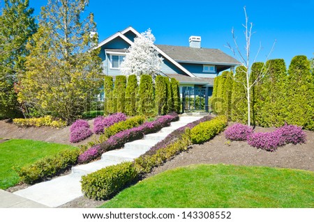 Big custom made luxury house with nicely trimmed and landscaped doorway and front yard lawn in the suburbs of Vancouver, Canada.