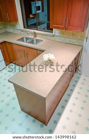 Counter of a luxury modern kitchen with some flowers in the vase. Interior design. Vertical.