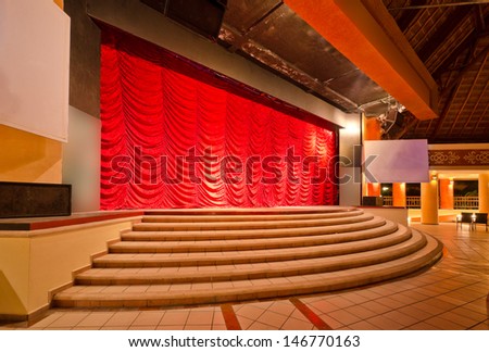 Theater stage with red curtains and steps. Theatrical scene,  the interior of the old theater of the luxury caribbean resort. Bahia Principe, Riviera Maya, Mexican Resort.