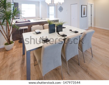 Nicely decorated and served living, lunch room table with the coffee, tea set and the kitchen at the back. Interior design.