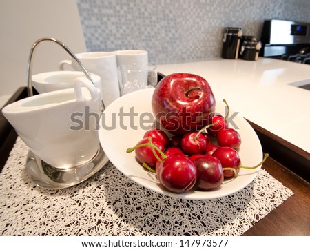 An apple and some cherries on the plate and the tea, coffee set aside.  Interior design.