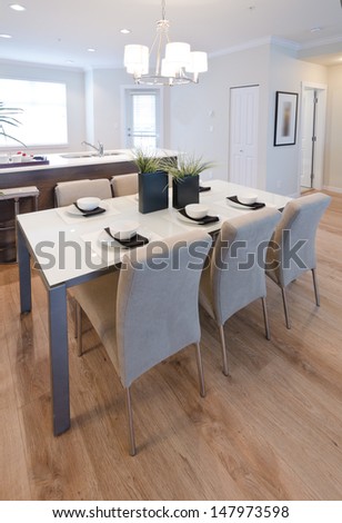 Nicely decorated and served living, lunch room table with the coffee, tea set and the kitchen at the back. Interior design. Vertical.