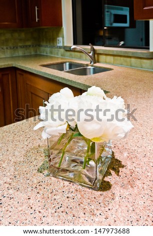 Some flowers in the vase on the counter of a luxury modern kitchen. Interior design. Vertical.