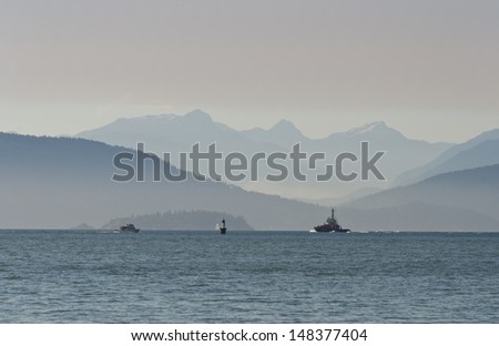 Gorgeous view at the marine scenery. A boat, ship, vessel moves across the ocean inlet  with the mountains and hills as a great background. Vancouver, Canada.