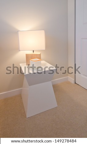 Decorative modern style night stand table with the night lamp in bedroom. Interior design.