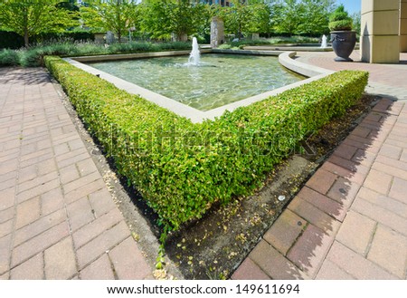 Landscape design. Nicely trimmed bushes  around fountain in the park. Vancouver. Canada.
