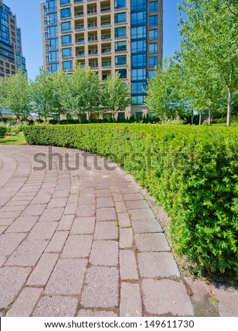 Landscape design. Nicely trimmed bushes and paved pedestrian sidewalk in the park. Vancouver. Canada. Vertical.