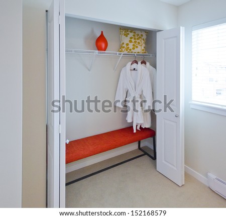 Two Bathrobes Hanging On A Racks And Shelve With Some Decorations As Vase And Pillow In The Closet. Interior Design.