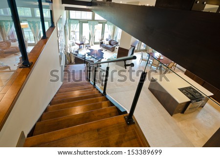 Entrance, stairs to the luxury upper home level with the spacious living room downstairs. View from atop. Interior design.