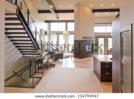 Outlook at the luxury spacious modern living room with the fireplace and stairs to the upper level. Interior design.