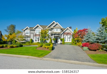 Big custom made luxury house with nicely trimmed and landscaped front yard lawn and long driveway in the suburbs of Vancouver, Canada.