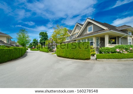 Nice and comfortable neighborhood. Houses  behind green fence on the empty street in the suburbs of Vancouver, Canada.