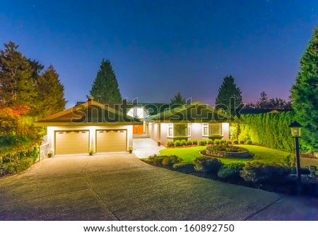 Big luxury house with two garages at dusk, night time in suburbs of Vancouver, Canada.