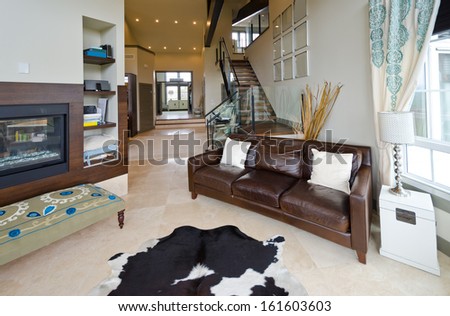 Outlook at the luxury spacious modern living room with the leather sofa, coach at the front and fireplace. Interior design.