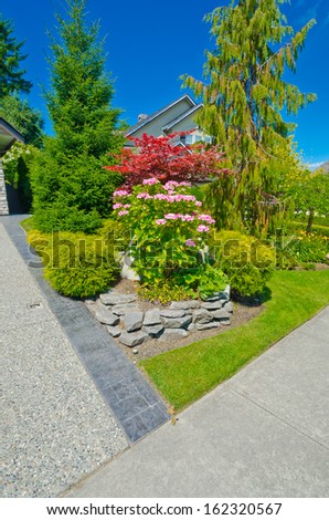 Some flowers and nicely trimmed bushes on the front yard in the suburbs of Vancouver, Canada. Landscape design.