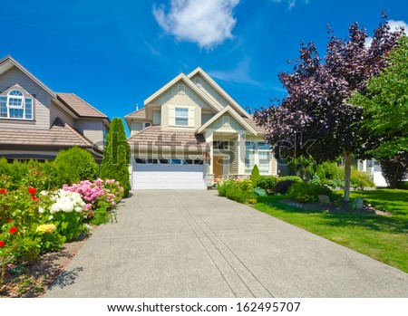 Big custom made luxury house with long driveway and nicely landscaped front yard in the suburbs of Vancouver, Canada.