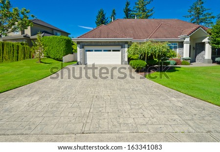 Big custom made luxury house with wide and long driveway and nicely trimmed and landscaped front yard lawn in the suburbs of Vancouver, Canada.