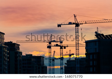 Construction site with cranes at sunset, sunrise, dawn time with the cranes as a silhouette. Vancouver, Canada.