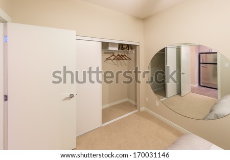 Room with the open empty closet, working closet, cupboard with some racks, hangers and big mirror. Interior design.
