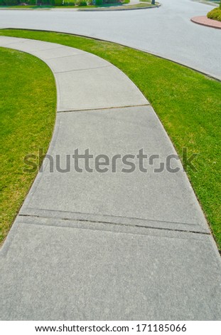 Nice and clean long, curved sidewalk, path at the empty street. Neighborhood scenery.