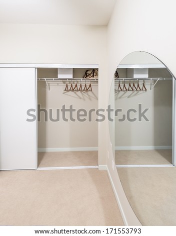 Room with the open empty closet, working closet, cupboard with some racks, hangers and big mirror. Interior design.