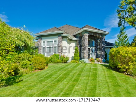 Big custom made luxury house with nicely landscaped and trimmed front yard and long and wide driveway in the suburbs of Vancouver, Canada.
