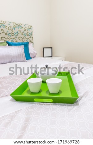 Decorative green color tray with the coffee set on the bed in the luxury master bedroom. Interior design. Vertical.
