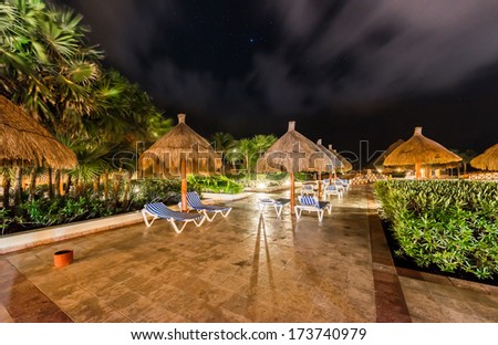 Beach umbrellas at swimming pool at  luxury caribbean resort at night, dawn time. Bahia Principe, Riviera Maya, Mexican Resort.