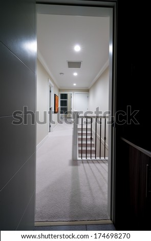 Perspective of corridor on the upper level of a house with the stairs and the room at the end. Interior design.