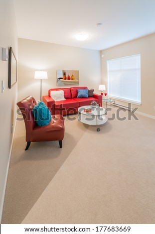 Luxury living suite of brand new townhouse. Nicely decorated modern family, living room with red color leather couch, chair and coffee table. Interior design. Vertical.