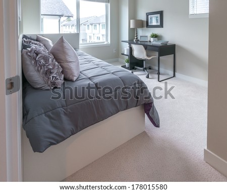 Luxury nicely decorated modern bedroom with some elements of den, home office with the table and the office chair at the back. Interior design of a brand new house.