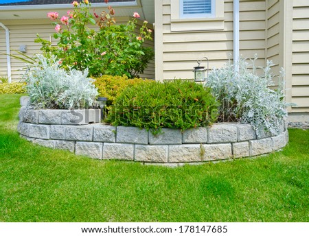 Some Flowers And Nicely Trimmed Bushes In The Stoned Flowerbed On The Front Yard In The Suburbs Of Vancouver, Canada. Landscape Design.