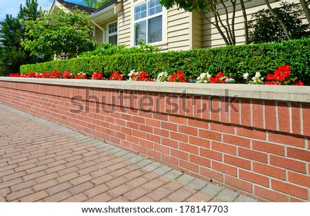 Some flowers and nicely trimmed bushes on the brick flowerbed and nicely paved yard in the suburbs of Vancouver, Canada. Landscape urban design.