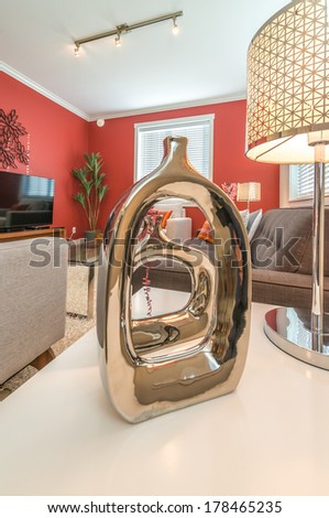 Fragment of a luxury living suite. Nicely decorated modern family, living room with decorative vase on the coffee table and red colored room. Interior design.