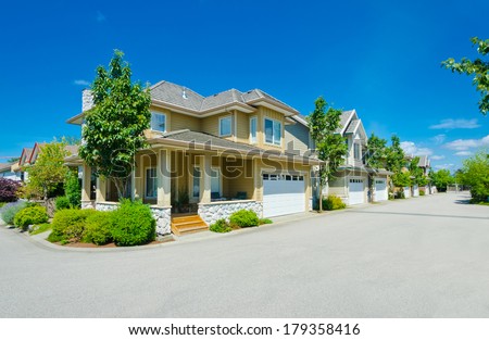 Nice and comfortable neighborhood. A House on the corner of empty street and a row, line of the houses with garages, homes in the suburbs of the North America. Canada.