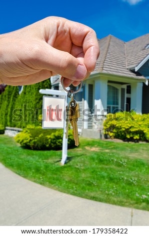 Hand holding the keys for a big custom made luxury house for sale, house of dream in the suburbs of Vancouver, Canada. Vertical.