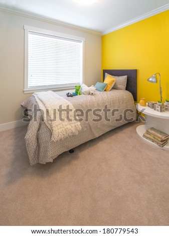 Modern comfortable, nicely decorated children bedroom painted in yellow. Interior design.