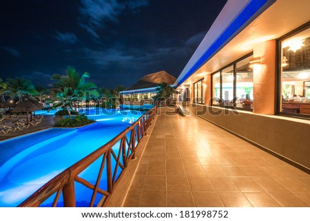 Perspective of promenade between swimming pool and a restaurant at luxury caribbean resort at night, dawn time. Bahia Principe, Riviera Maya, Mexico.