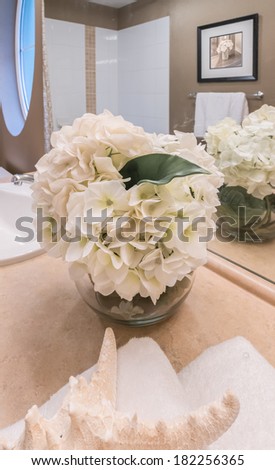 Fragment of nicely decorated washroom, bathroom with the vase and some flowers. Interior design. Vertical.
