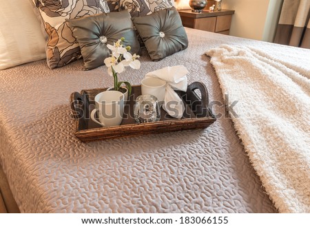 Decorative tray with tea, coffee set and flower on the bed in the luxury master bedroom. Interior design.