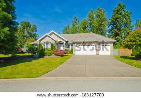 Big custom made luxury house with nicely landscaped front yard and long and wide driveway to the triple doors garage in the suburbs of Vancouver, Canada.