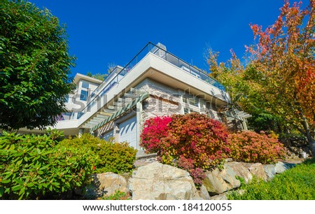 Big custom made luxury house with nicely landscaped front yard with some colorful bushes and rocks in the suburbs of Vancouver, Canada.