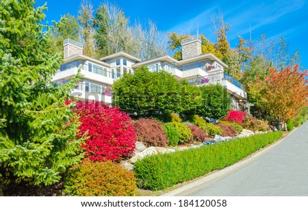 Big custom made luxury house with nicely landscaped front yard with some colorful bushes in the suburbs of Vancouver, Canada.