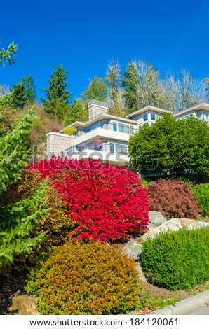 Big custom made luxury house with nicely landscaped front yard with some colorful bushes in the suburbs of Vancouver, Canada. Vertical.